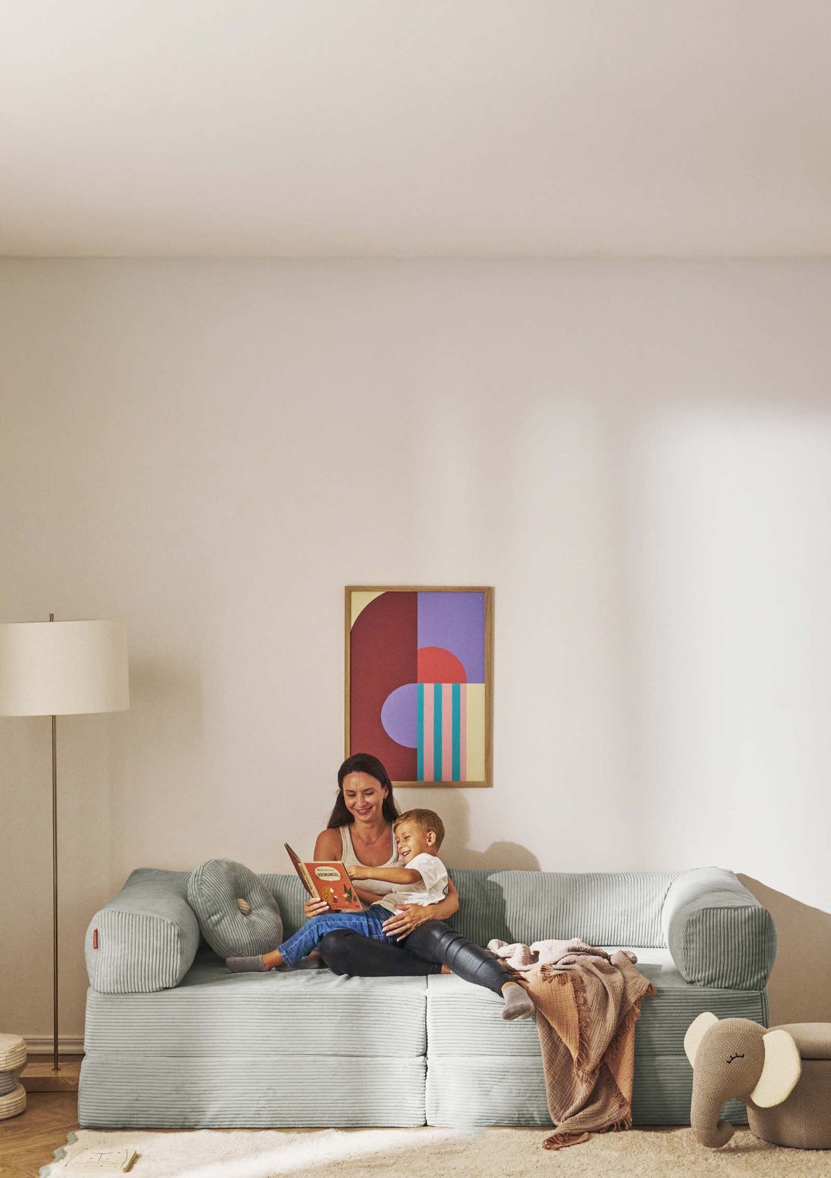 Mutter und Kind beim Lesen auf dem Funzy Family Sofa Cord Salbei Grün