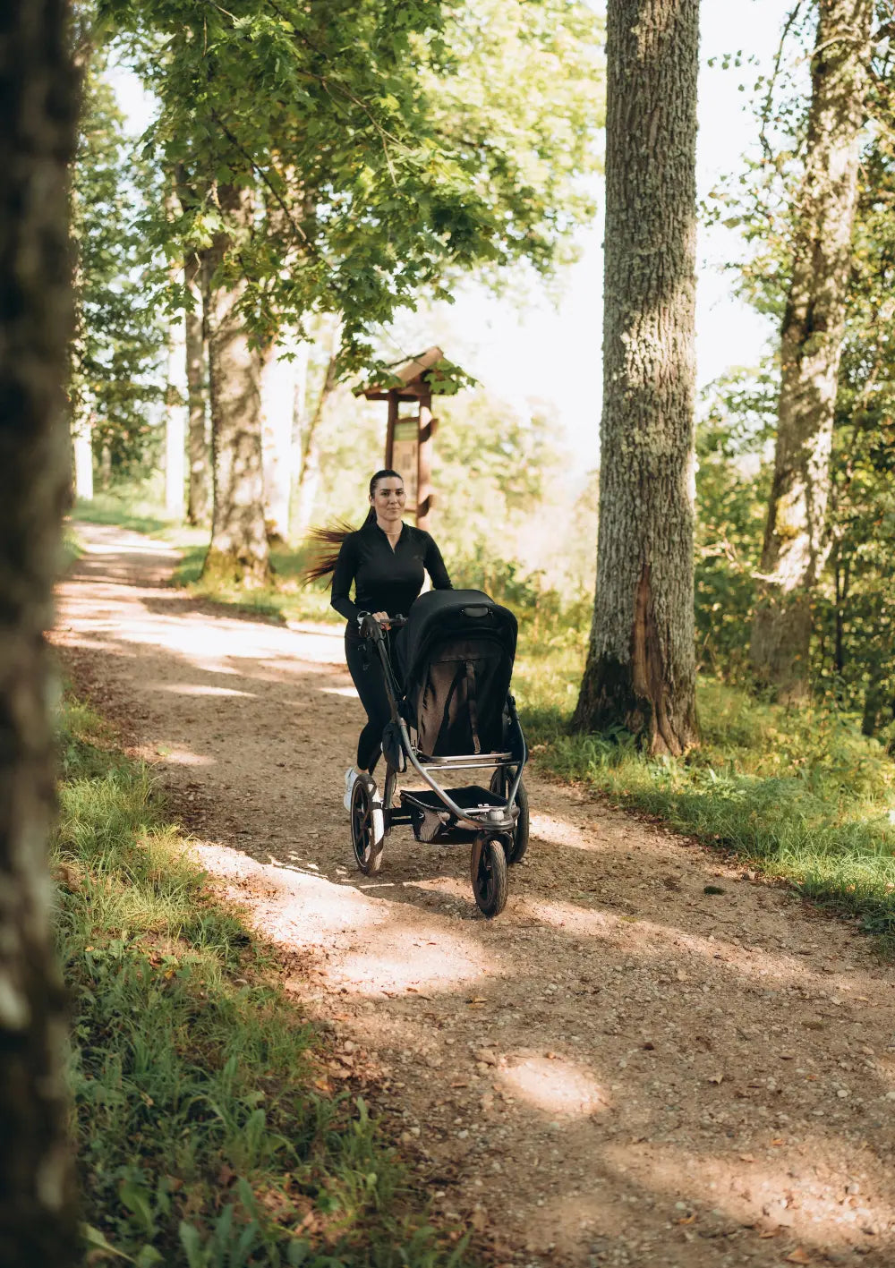 Frau beim Joggen im WAld mit dem tfk Kinderwagen-Set 'pro' Schwarz