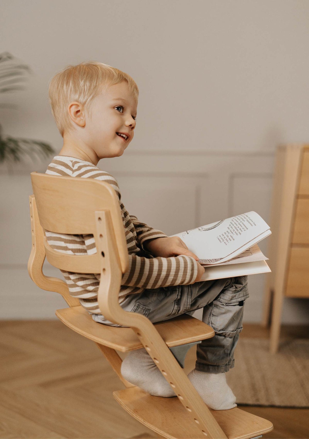 Kind schaut sich ein Buch an im Leander Hochstuhl 'Louie' Buche
