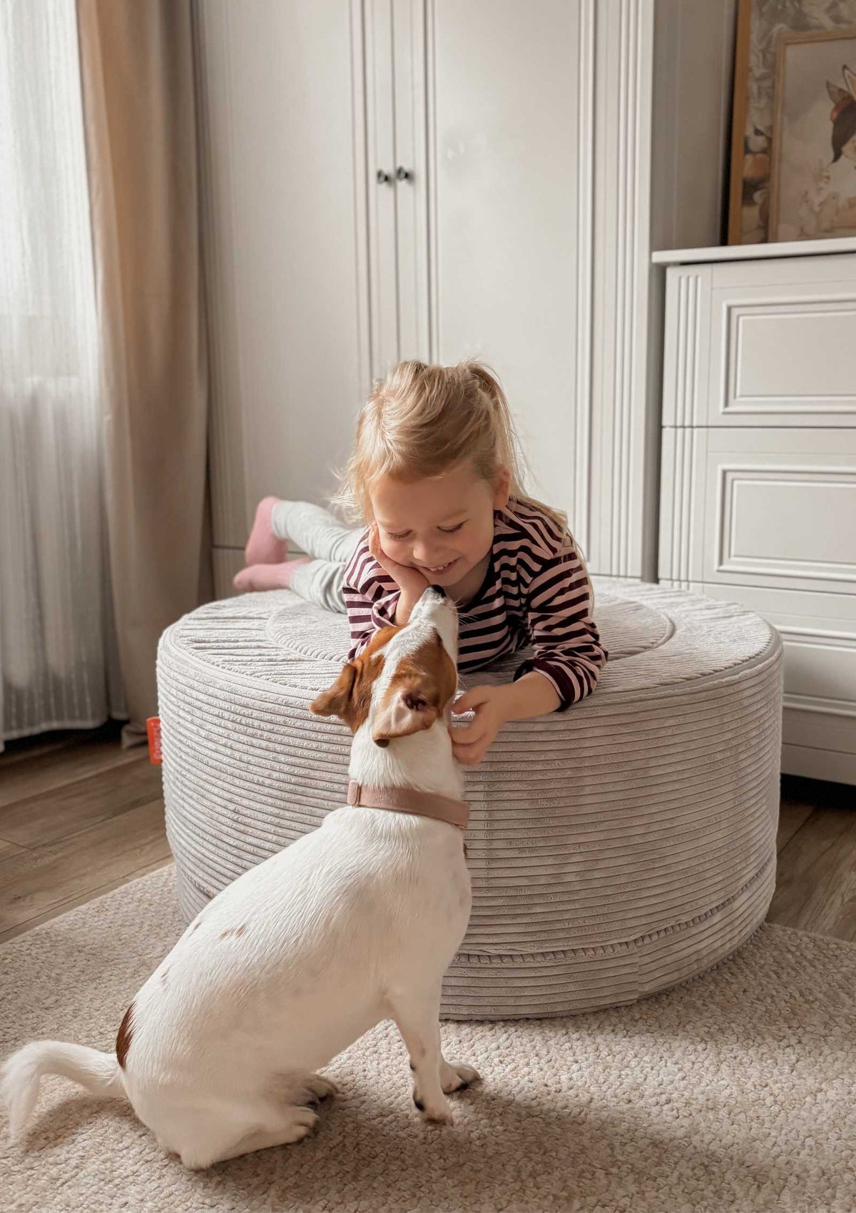 Mädchen liegt auf Funzy Donut Cord Koala Grau und streichelt Hund