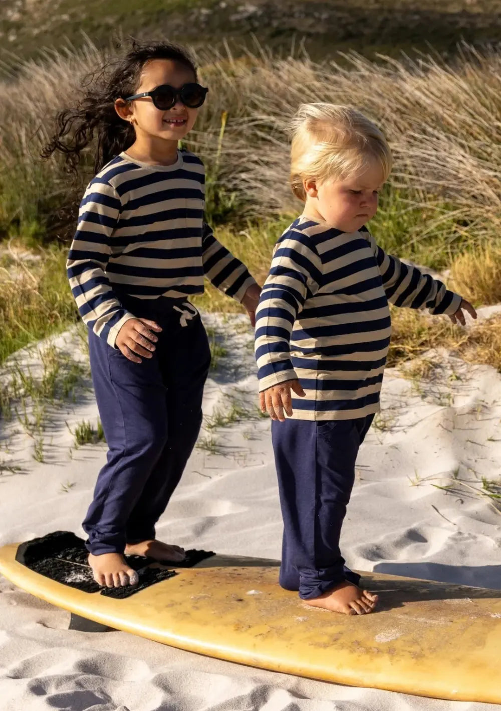 Kinder spielen am Strand – bkleidet mit Cloby Jogginghose UPF 50+ Navy und Langarmshirt UPF 50+ Navy/Sandy Stripe